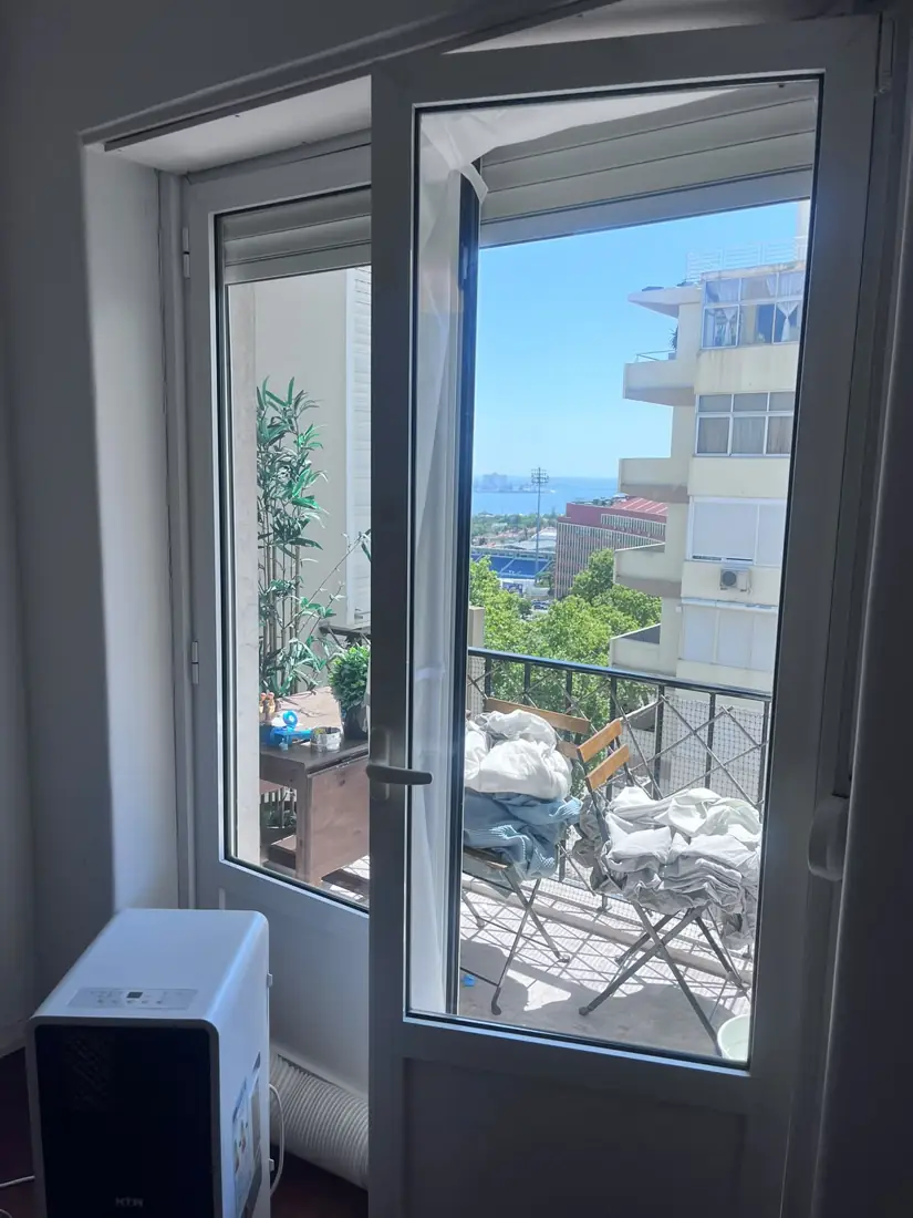 Ar condicionado portátil de aluguer junto a uma porta de varanda em Belém