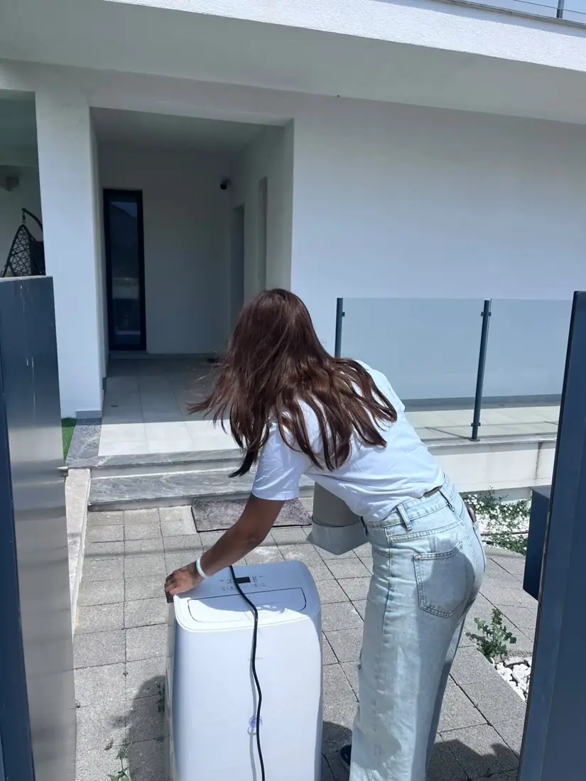 Renata da AC Rental Lisbon a ligar um ar condicionado portátil numa entrega em Grande Lisboa