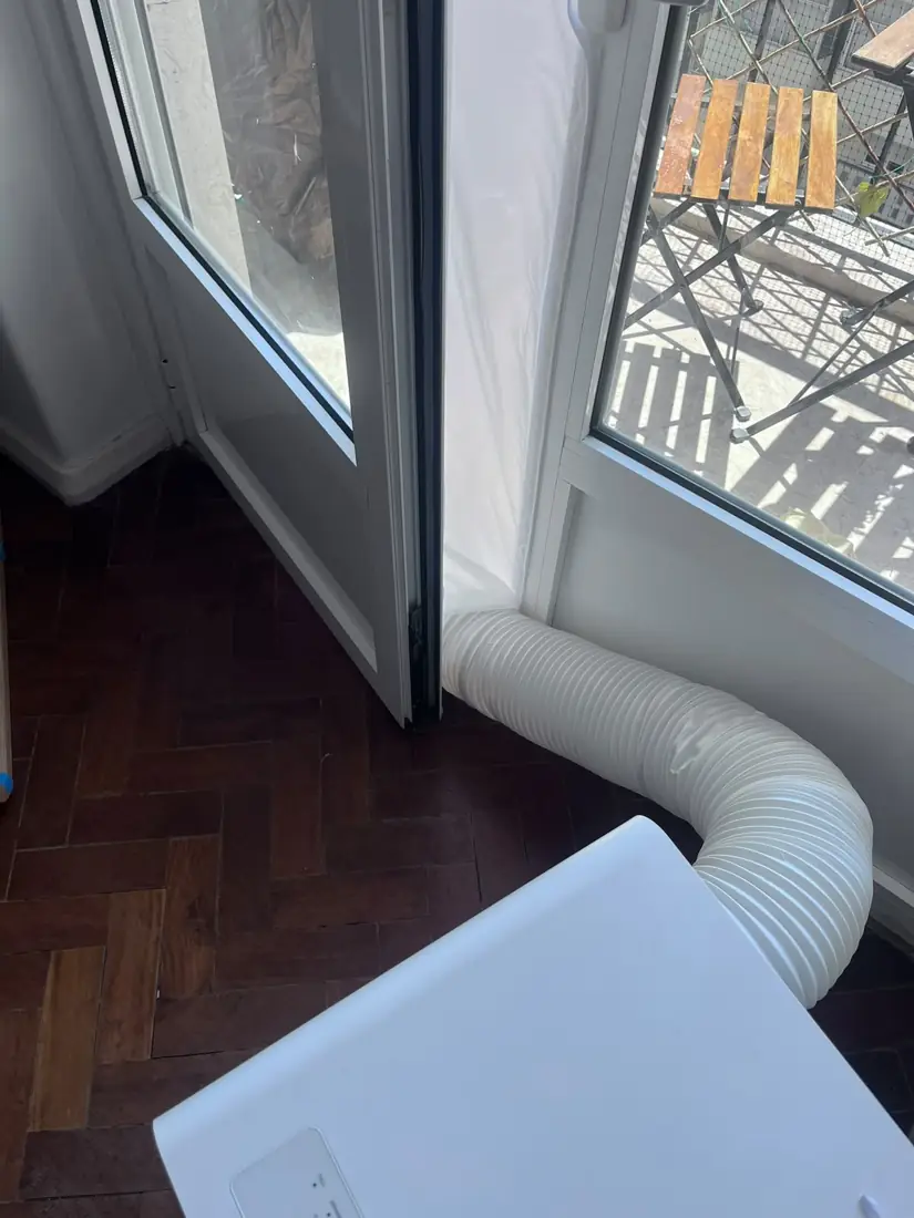Tubo de exaustão de um ar condicionado portátil a sair por uma porta de varanda em Belém